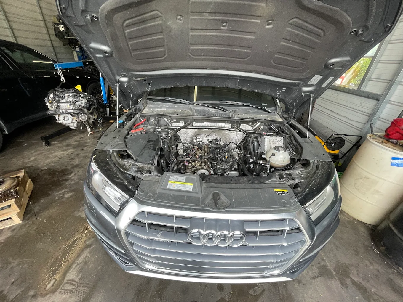 Audi Q5 mid-repair at Mentor Auto Service with the hood open and engine bay being serviced.
