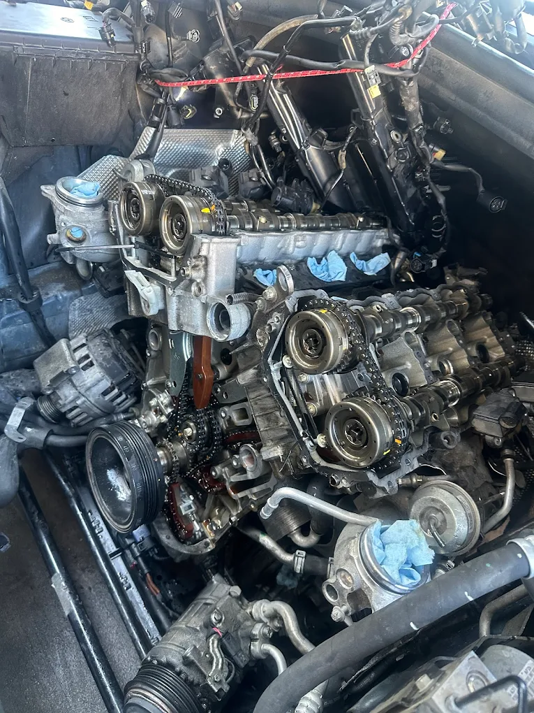Close-up of an exposed European engine with timing chains and camshafts visible during a timing job at Mentor Auto Service.